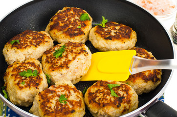 Pan with fried meat patties on white plate