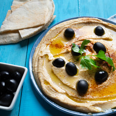 Traditional hummus plate with black olives and paprika