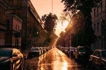 Parked cars in midtown of summer city Voronezh, summer rain and sunset sun in old European city