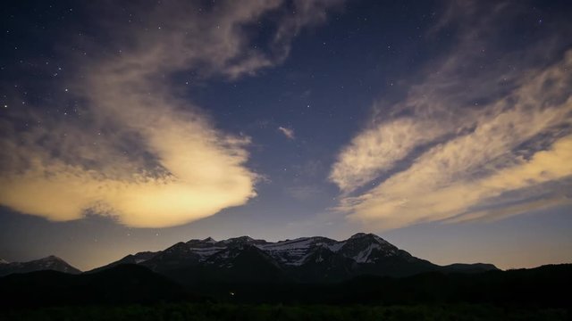 Time lapse of  clouds fading and stars shining in the nights sky after dusk fades into night overlooking Timpanogos Mountain in Utah.