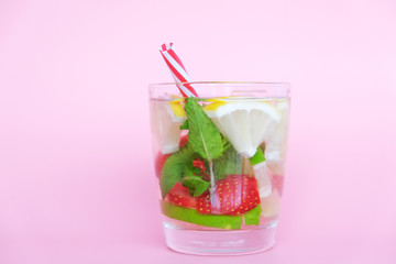 Summer bar concept. Ingredients: gin, soda, mint leaves, strawberry, lime and lemon. Alcohol summer drink with fresh fruits on pink background.