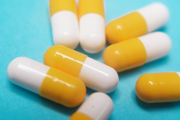 Pills on a blue background. Assorted pharmaceutical medicine pills, tablets and capsules, health macro. Heap of various pills on color background. Yellow pills