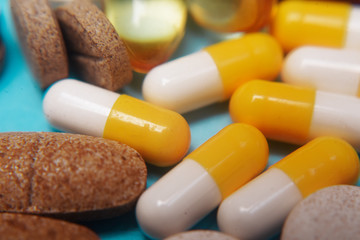 Pills on a blue background. Assorted pharmaceutical medicine pills, tablets and capsules, health macro. Heap of various pills on color background. Yellow pills