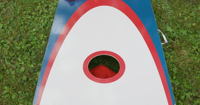 Playing Cornhole Game in Yard with Red, White and Blue Board and Bags