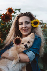 A young woman and her small dog in a sunflower field