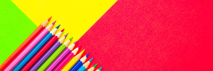 Colorful background with many pencils crayons pastels lined up on multi color backdrop - Top view flat lay