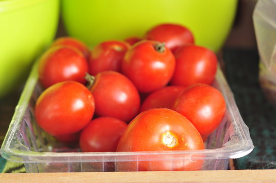 Ripe red tomatoes are stored in a plastic tray
