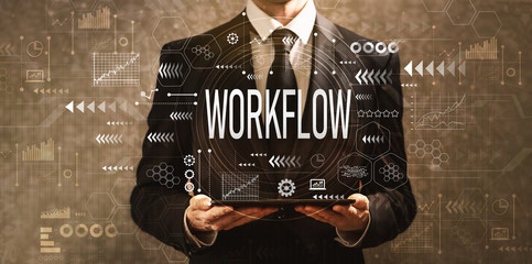 Workflow with businessman holding a tablet computer on a dark vintage background
