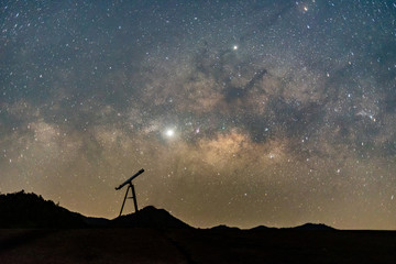 Silhouette of telescope against  milky way galaxy with stars and space dust in the universe.