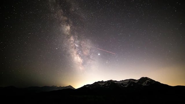 Night to day time lapse of the Milky Way over timpanogos mountain in Utah as the stars move through the sky and sun lights up the mountain peaks.