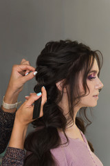 Fototapeta premium Master of hairstyles with coarse-toothed comb fluff texture to hairdo. Beauty service concept. Delicate and fun customer service. Background. Copy space. Space for text