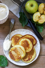 Homemade apple fritters with sour cream, coffee and green apples on a wooden background. Rustic style.