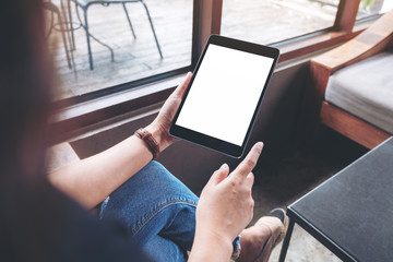 Mockup image of a woman holding black tablet pc with blank white screen while sitting and relaxing in cafe