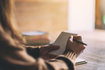 Closeup image of a woman holding and writing on blank notebook