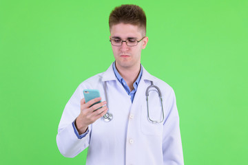 Young handsome man doctor with eyeglasses using phone
