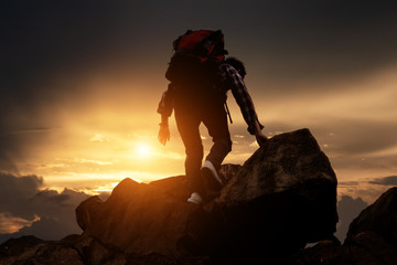 Hikers climbing up mountain cliff in sunset. Concept of limits of life and Hiking success full.