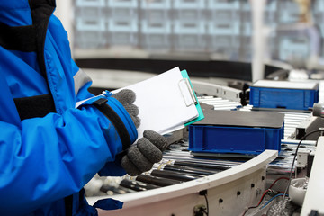 Closeup shooting hand of worker with clipboard checking plastic crate for fruits and vegetables...