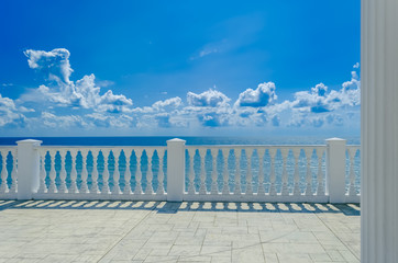 Terrace with white balusters to amazing views of the sea, sky and white clouds.