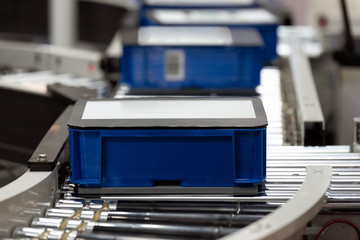 Plastic crate for fruits and vegetables loading on conveyor machine in the warehouse.