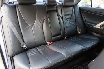 View to the interior of car with dashboard, rear seats, black leather after cleaning before sale on parking