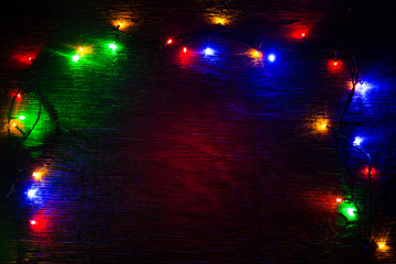 multicolored Christmas lights on a wooden background