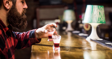 Bearded man shots cocktail. Tequila shot. Colorful cocktails at the bar. Tequila shots, vodka,whisky, rum. Drinking alcohol into shot glasses in a nightclub or bar. Barman in pub. Bearded man in pab