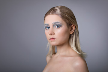 Obraz premium The face of a young woman with delicate face art in the winter style. Conceptual female makeup.