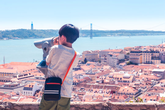 Little boy playing with a binoscope on the observation deck overlooking the old town