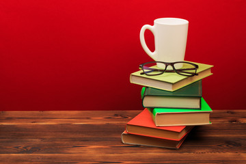  pile of old books with mug , panorma, good copy space  on red background