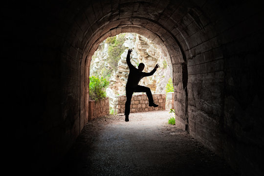Man jumping in a dark tunnel - Powered by Adobe