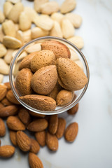 Mandeln als ganze Nuss, ungeschält und blanchiert geschält auf Marmor Hintergrund