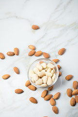 Geschälte und ungeschälte Mandeln in Glas Schale auf Marmor Hintergrund