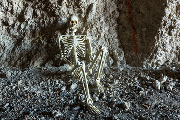 Skeleton in a dark cave in the ground lying on rocks