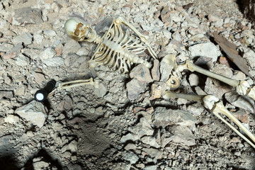 Skeleton in a dark cave in the ground lying on rocks