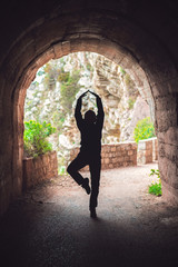 Woman practicing yoga in a dark tunnel