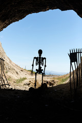 Skeleton silhouette in the mouth of a gated mine stay out stay alive