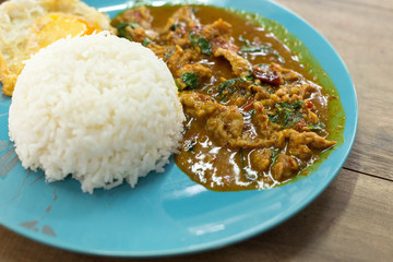 Fried curry paste and rice in a blue plate on wooden table