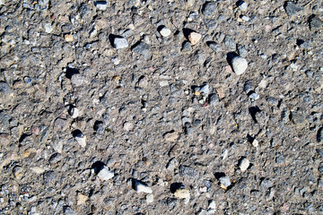 Stone asphalt texture of road and pebbles circle. Grey asphalt road and and a hand-made circle of gravel. Background pebble and gravel