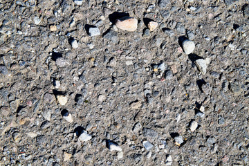 Stone asphalt texture of road and pebbles circle. Grey asphalt road and and a hand-made circle of gravel. Background pebble and gravel