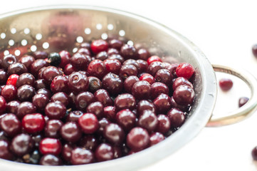 Fresh cherry with water drops in an iron bowl on a white background