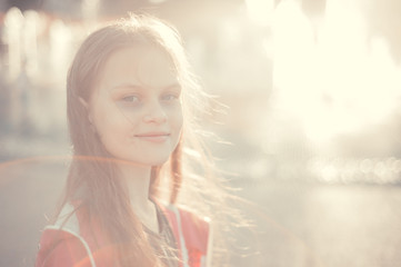 Beauty portrait of girl outdoors. Attractive nice cute young girl with smile on her face near the fountain in summertime at sunset. Closeup portrait of cheerful girl.