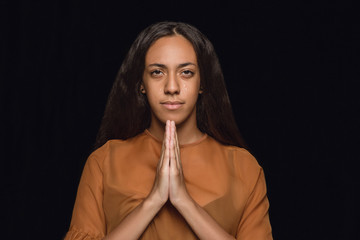 Close up portrait of young african-american woman isolated on black studio background. Photoshot of real emotions of female model. Facial expression, human nature. Praying and crying.