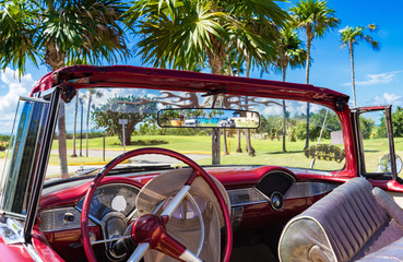 Amerikanischer roter Cabriolet Oldtimer parkt unter Palmen in Varadero Kuba - Serie Kuba Reportage