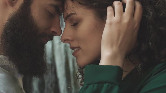 profile portrait of a man with a beard and a woman with eyes closed who bent head to head against the backdrop of sparkling waterfall splashes