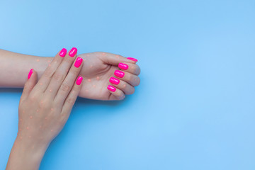 Stylish trendy female manicure. Beautiful neon plastick pink nails on blue background. Nail polish. Art manicure. Modern style.