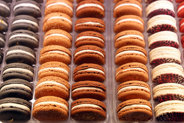 Macaroons in a row close up, colorful sweet background. Orange and chocolate almond cookies with filling, bright colours