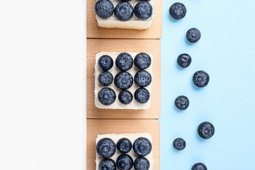 Tasty blueberry cakes on color background