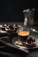 Coffee and chocolate cake with berries on a dark plate. Breakfast, coffee and dessert