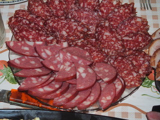 On a plate laid out sliced pieces of sausage and meat. Home feast.