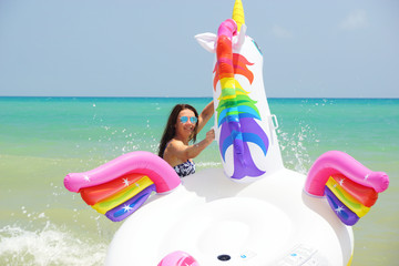 Young woman swimming with unicorn in Mediterranean sea in vacation. Guardamar, Spain